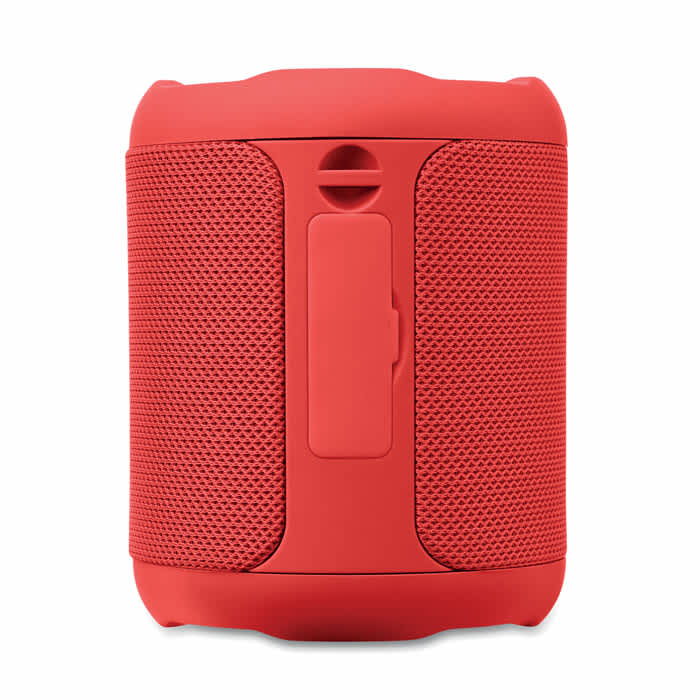 A red portable speaker with a textured surface and a central button. It has an attached clip for easy carrying.