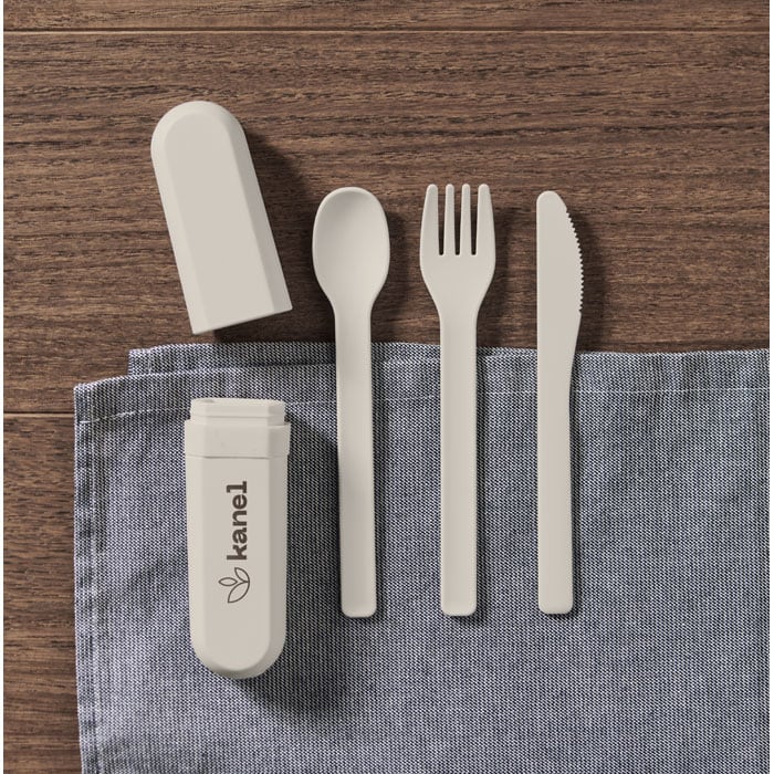 A portable cutlery set in light grey, including a spoon, fork, knife, and storage case, laid on a blue cloth.