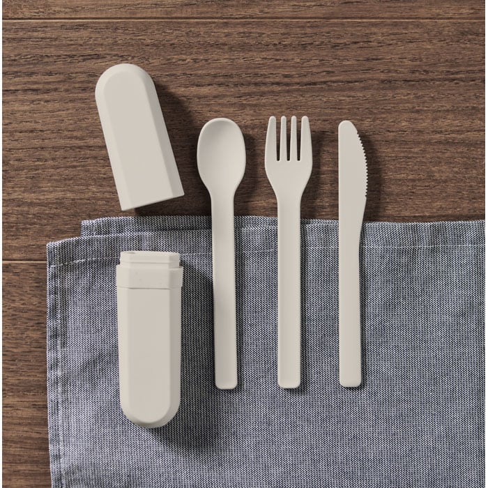 A portable cutlery set in light beige including a spoon, fork, knife, and case, placed on a grey cloth.