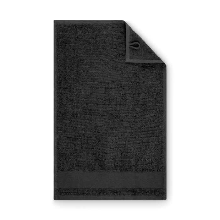 A black towel with a textured surface and a hanging loop in the corner. The towel has a simple, clean design.