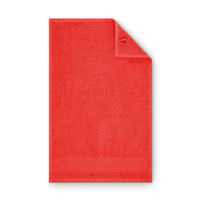 A red bath towel with a hanging loop, made of absorbent fabric, featuring a bordered edge at the bottom.