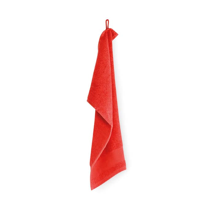 A red towel hung up with a hanging loop. The towel has a soft texture and is vibrant in colour.