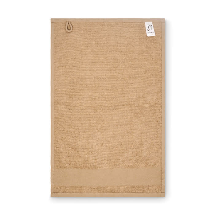 A towel in a sandy beige colour with a loop for hanging and a small tag.
