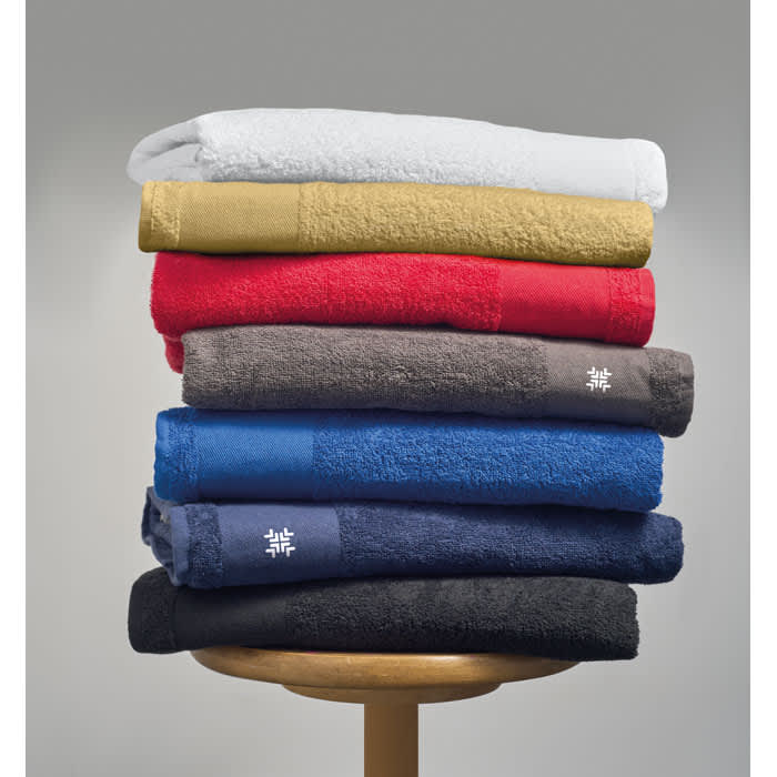 A stack of towels in white, gold, red, grey, blue, and black, featuring a logo on some towels.