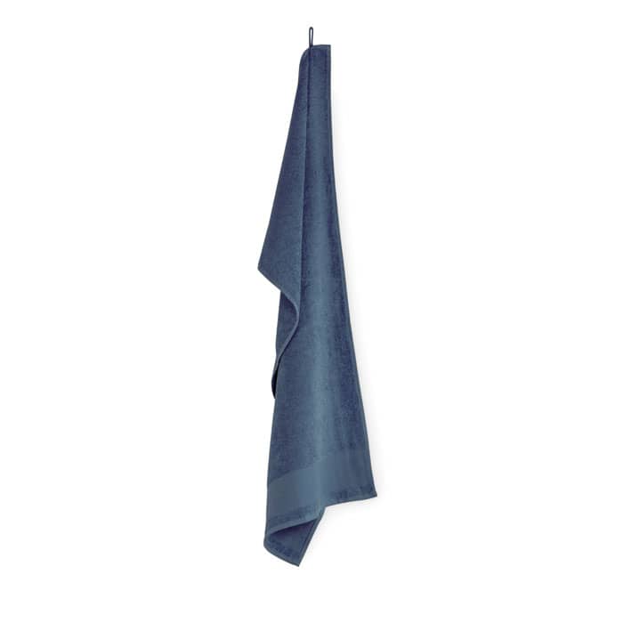 A blue towel hanging vertically, featuring a smooth texture and a simple design. The towel has a subtle logo detail.