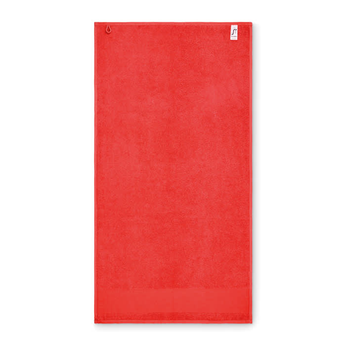 A red towel with a hanging loop, featuring a small branded label on one corner.