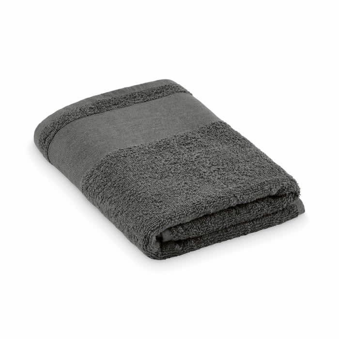 A folded towel in a dark grey colour, featuring a textured border. The towel has a simple design and appears soft.