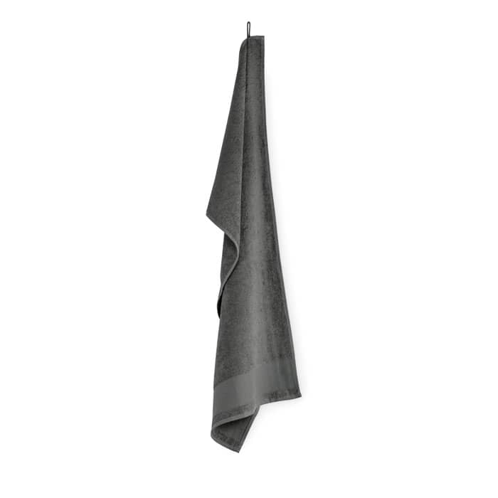 A grey towel hangs on a hook, featuring a smooth texture and simple design. It has a subtle branding detail.