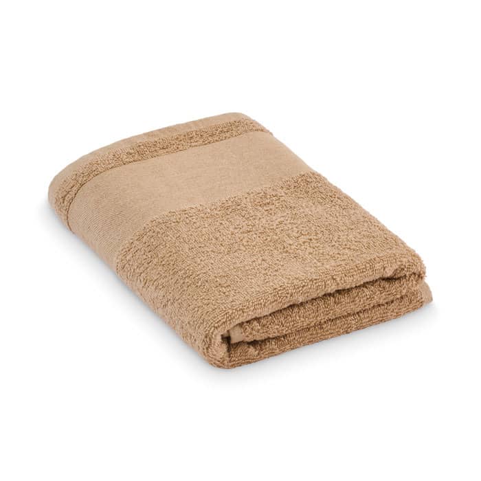 A folded towel in a warm tan colour with a textured border and smooth section. It has a simple, plush design.