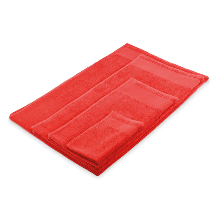 A set of red towels including a bath towel, hand towel, and face cloth, displayed neatly together.