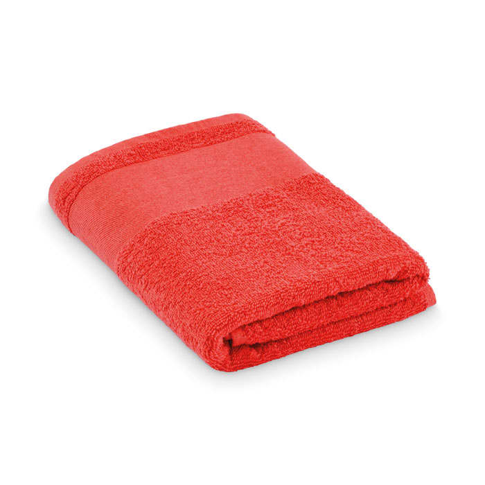 A red towel folded neatly, featuring a textured band in a slightly darker shade of red. It has no visible branding.