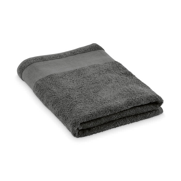 A grey towel folded neatly with a textured edge and a smooth top layer. It has a simple design and a soft appearance.