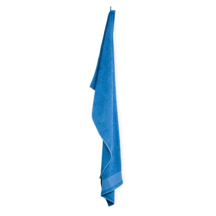 A blue towel hanging vertically, featuring a simple design and a small logo on the lower edge.