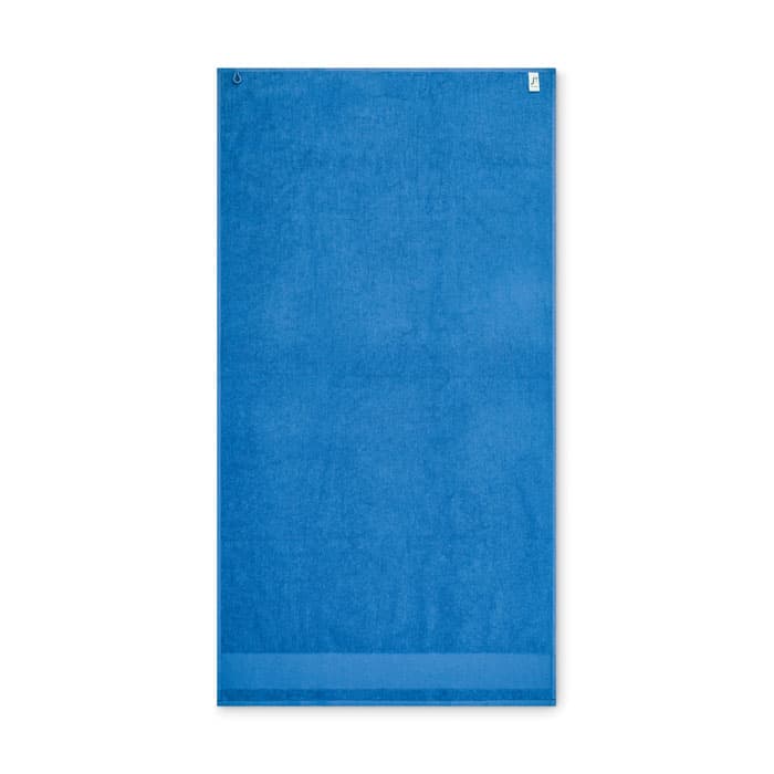 A blue beach towel with a textured surface and a hanging loop at the top. It has a small branding logo.