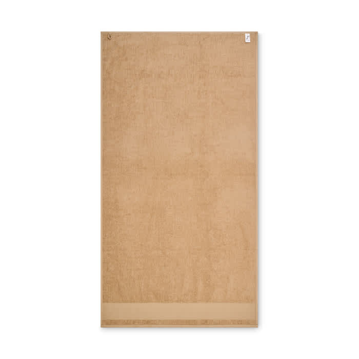 A towel in a sandy beige colour with a simple, clean design and a hanging loop. It features a logo.