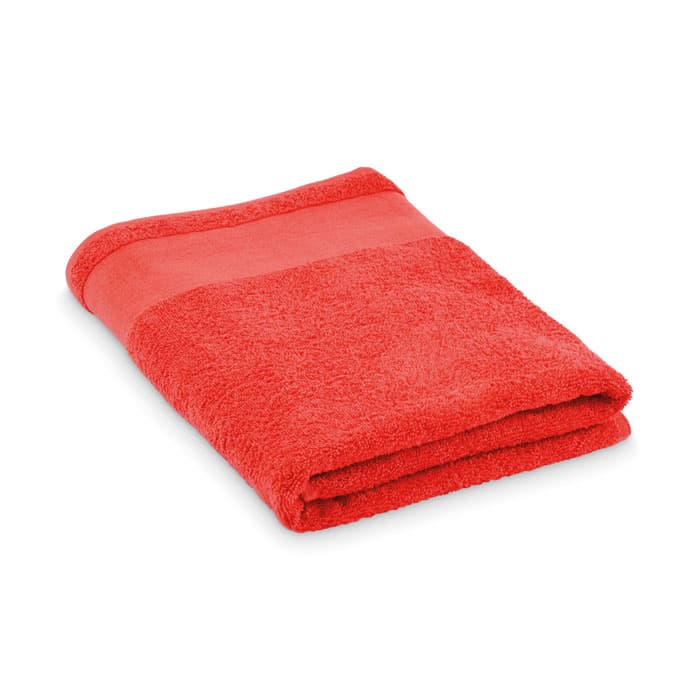 A red towel folded neatly, featuring a smooth border at the top. It has a soft, fluffy texture.