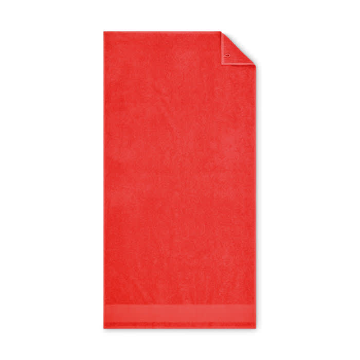 A red towel with a smooth surface and a folded corner, featuring a simple design without any logos.
