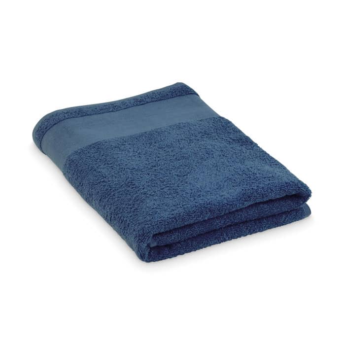 A folded towel in a deep blue colour with a textured surface and a flat band at one end. It has a branding logo.