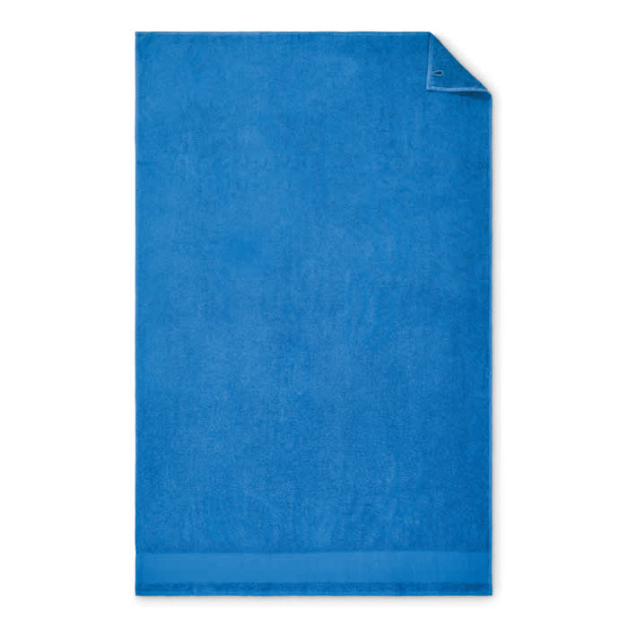 A blue towel with a smooth texture, featuring a folded corner and a simple design.