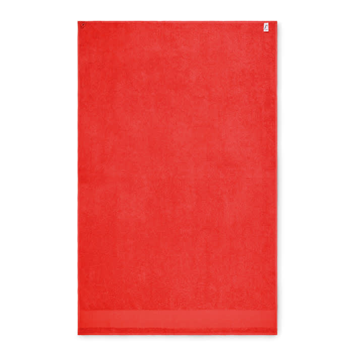 A red beach towel featuring a plain design and a logo in the corner. Made from soft, absorbent material.
