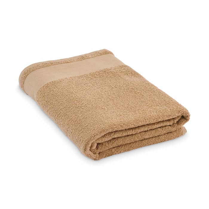 A folded towel in a warm beige colour, featuring a smooth band running along one edge. It includes a brand logo.