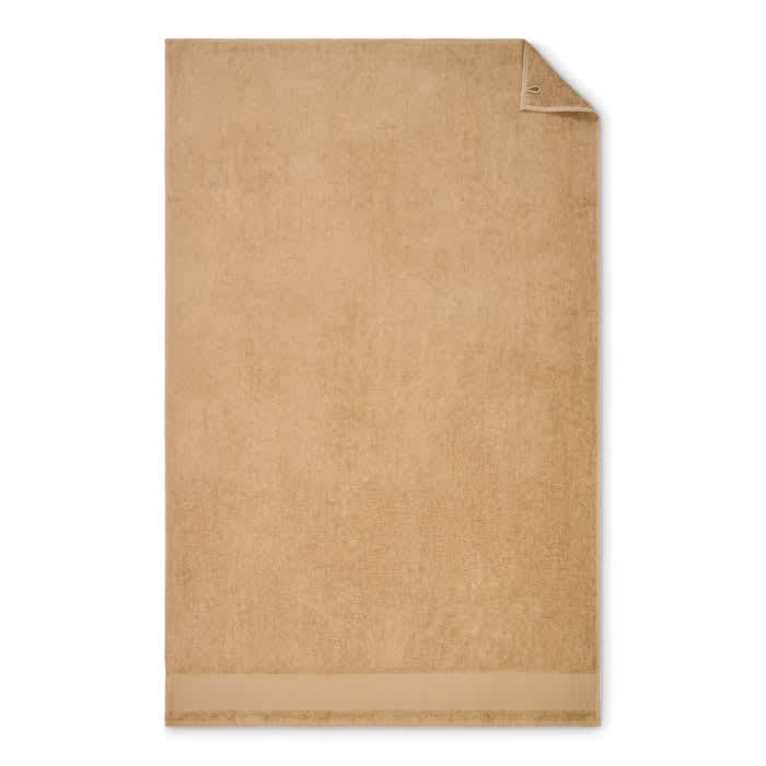 A soft, tan-coloured towel with a folded corner, featuring a plain design. It includes a small logo.