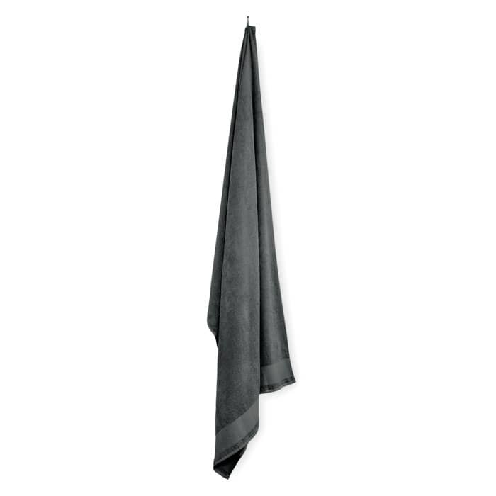 A dark grey towel hanging, with a smooth texture and a slightly reflective surface. It has a simple design.