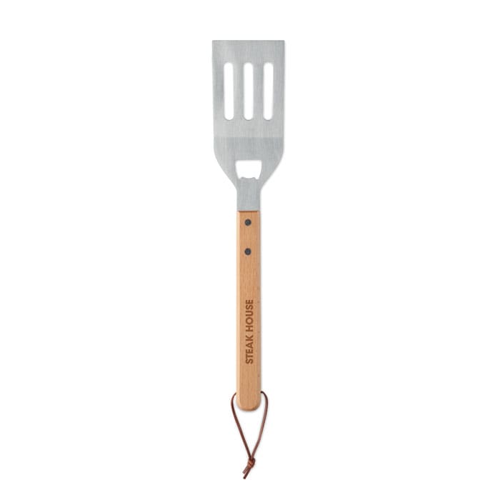A stainless steel spatula with a wooden handle, featuring a logo and a leather loop for hanging.