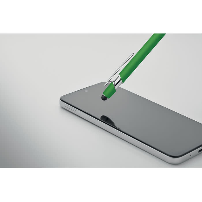 A green pen rests on a smartphone's glossy black screen, reflecting light with a sleek design.