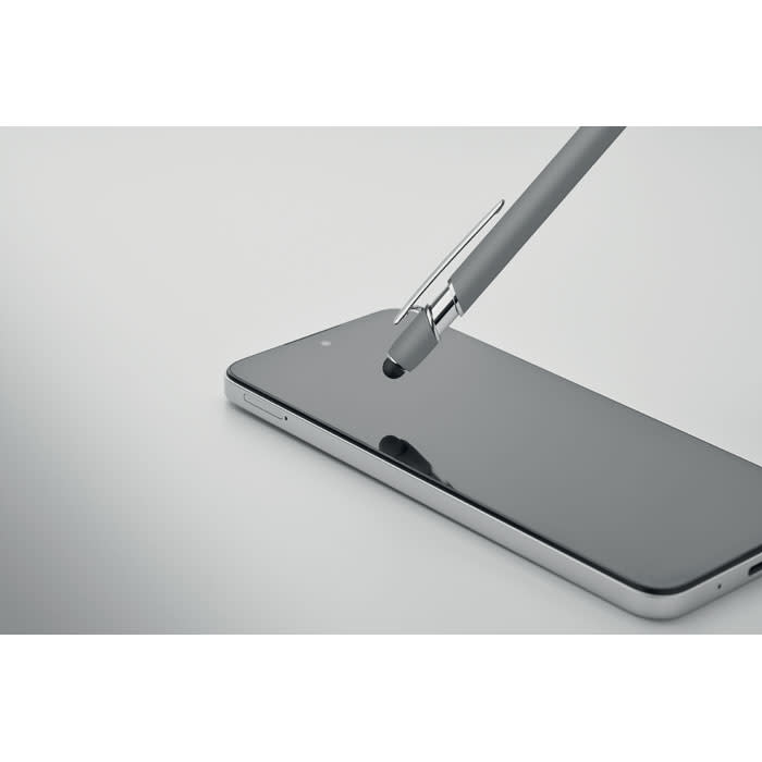 A sleek smartphone with a reflective black screen and a grey pen resting on top, featuring a metallic clip.