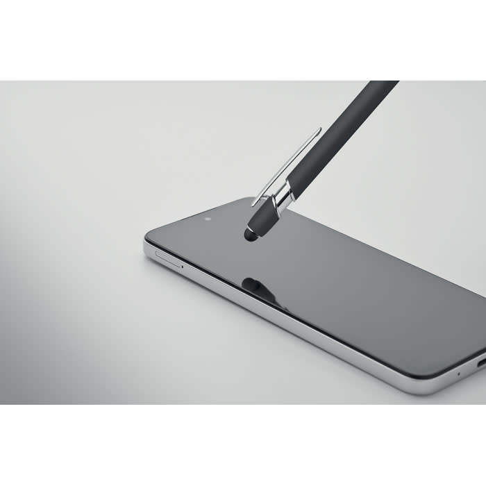 A black stylus pen resting on a sleek smartphone screen, reflecting light in a minimalistic setting.