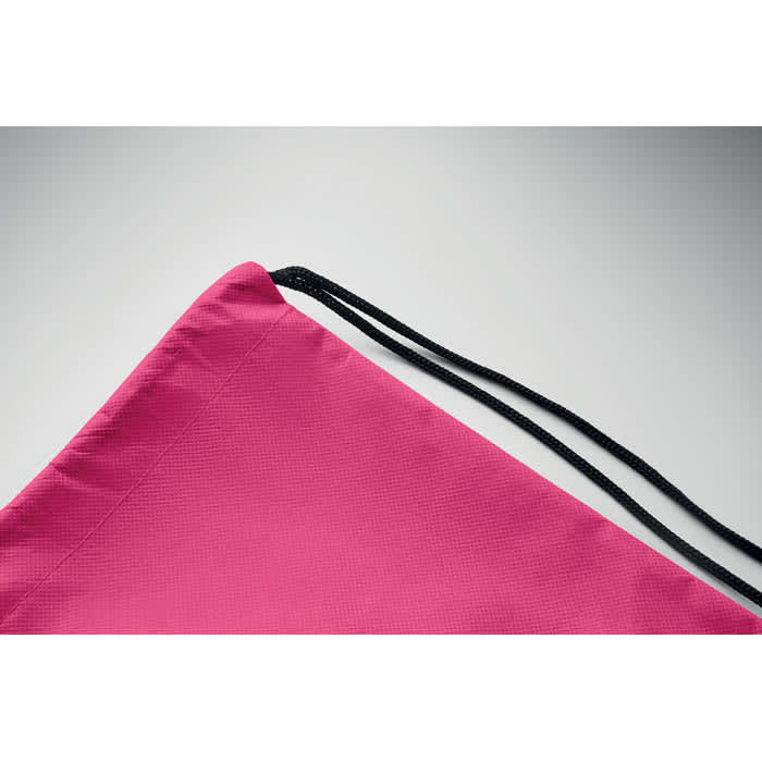 A drawstring bag in bright pink with black cords, featuring a solid, textured surface.