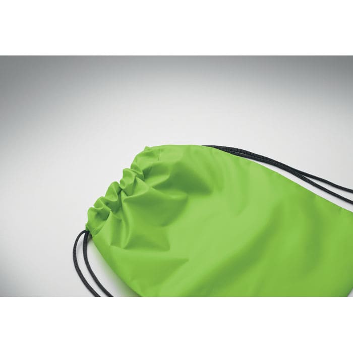 A green drawstring bag with black cords, featuring a simple design and no visible logos.