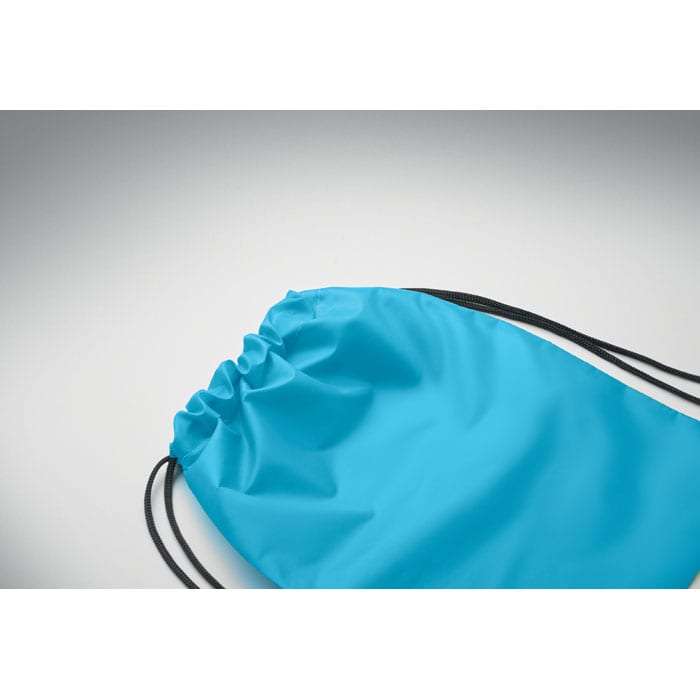 A drawstring bag in bright blue with black cord closures, featuring a smooth, shiny surface.