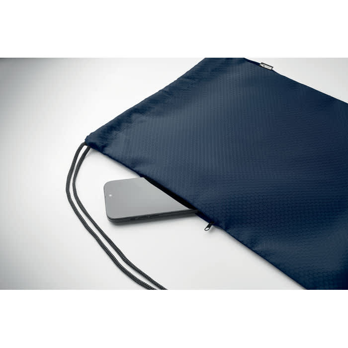 A drawstring bag in navy blue with a smooth texture, partially open to reveal a grey smartphone inside.