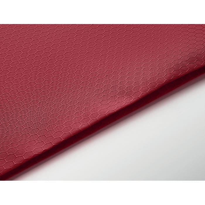 A textured red fabric with a hexagonal pattern is displayed, featuring a smooth edge.