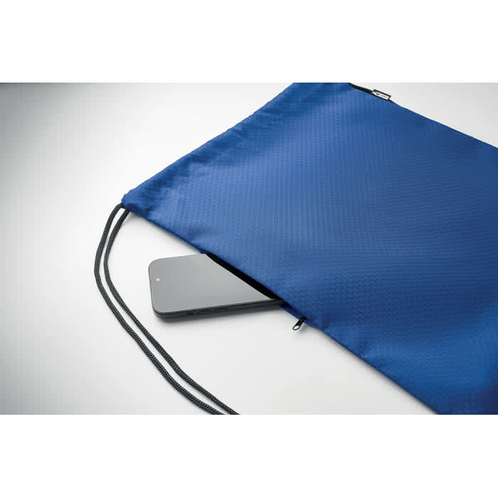 A blue drawstring bag with a smartphone partially visible inside. The bag features a logo on the front.