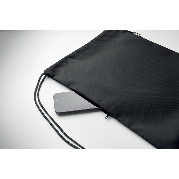 A black drawstring bag with a mobile phone partially visible inside. The bag features a textured fabric.