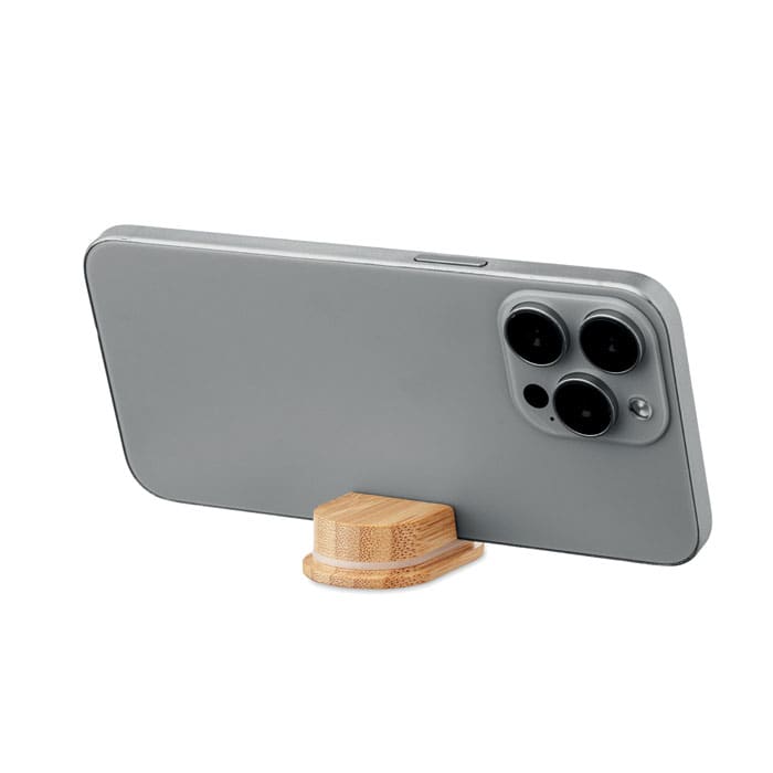 A phone resting on a small bamboo stand, featuring a grey case and three rear cameras.