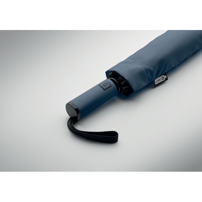 A blue umbrella with a black handle, partially closed, featuring a branding label on the side.