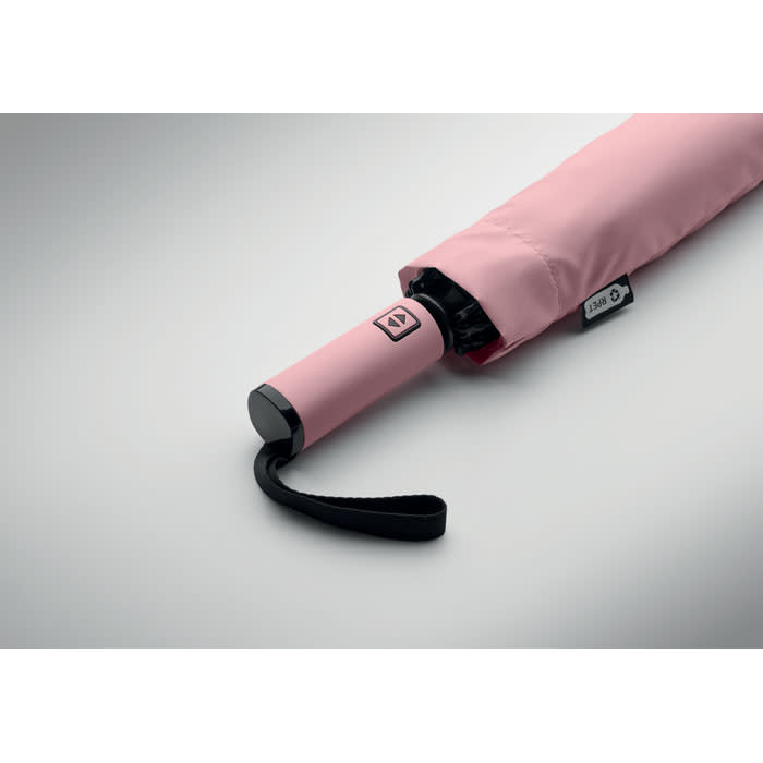 A pink umbrella with a black handle and a looped strap, partially opened, showcasing its sleek design.
