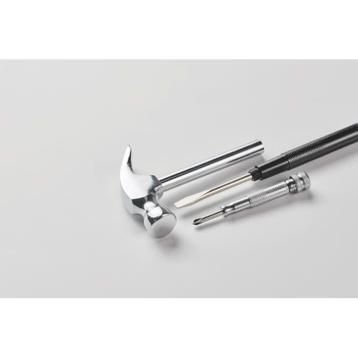 A metallic hammer alongside a screwdriver and a precision driver, all set on a light grey background.