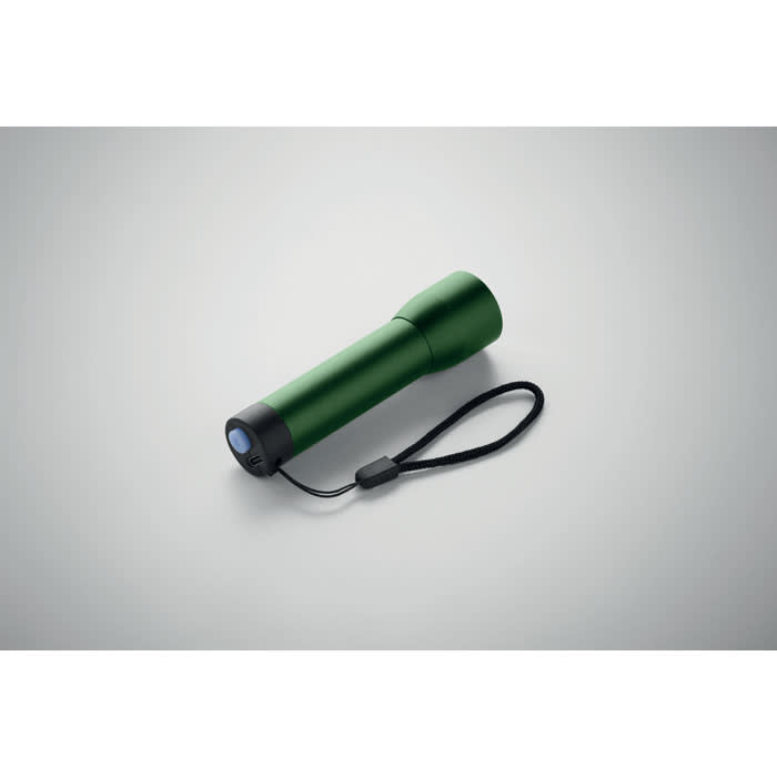 A green torch with a strap, featuring a rounded body and a front lens, resting on a light background.