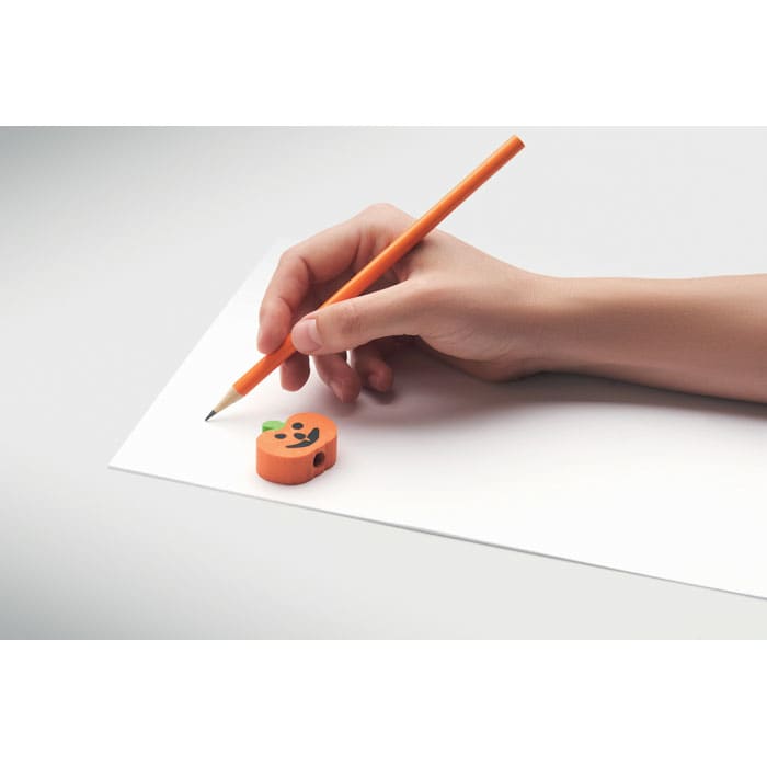 An orange pencil and a small pumpkin-shaped eraser resting on a blank sheet of paper.