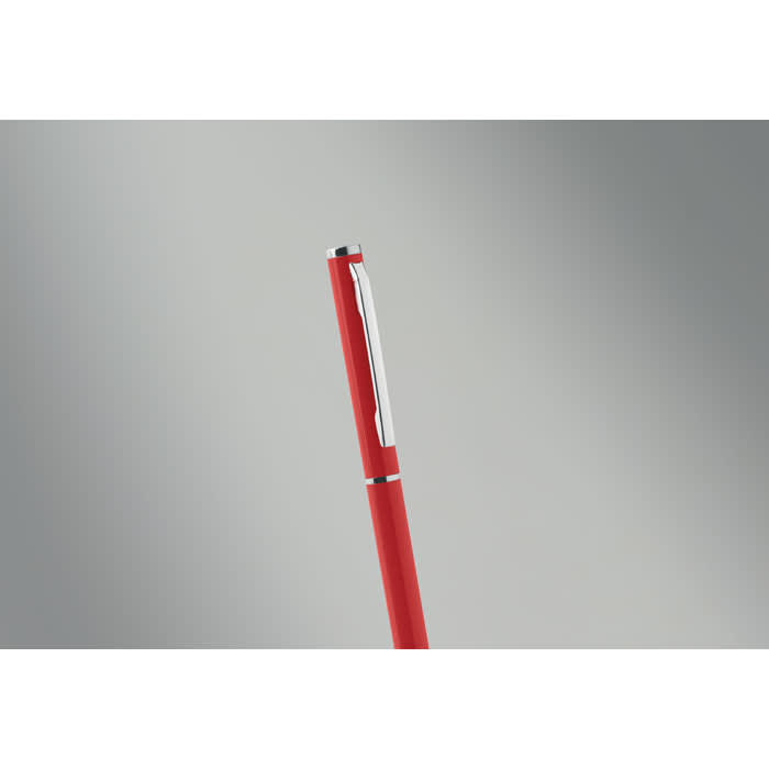 A red pen with a silver clip, set against a neutral grey background. It features a sleek design.