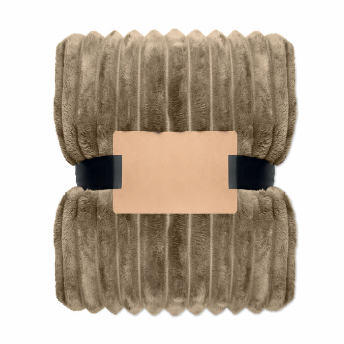 A plush, rectangular blanket in a soft tan colour, wrapped with a simple band. It features a textured, ribbed design.