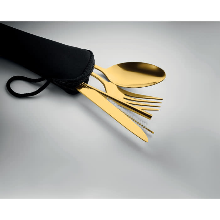 A black pouch containing gold-coloured utensils including a spoon, fork, and knife. The pouch has a drawstring closure.
