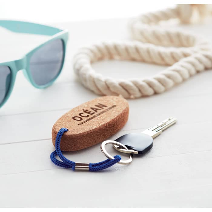 A keychain with a cork float, blue cord, and a key, accompanied by sunglasses and a rope.
