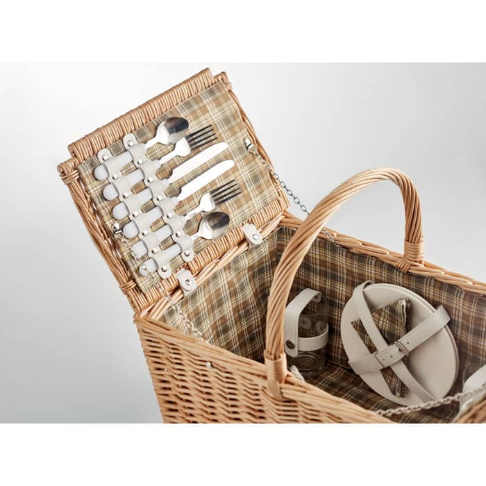 A picnic basket with cutlery and plates neatly arranged inside, featuring a plaid lining and a woven exterior.