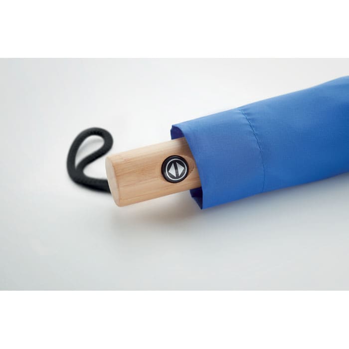A blue umbrella with a wooden handle and a circular logo on the handle.